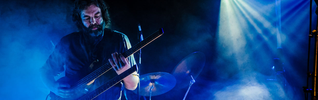 A guitarist at a concert with light beams and haze